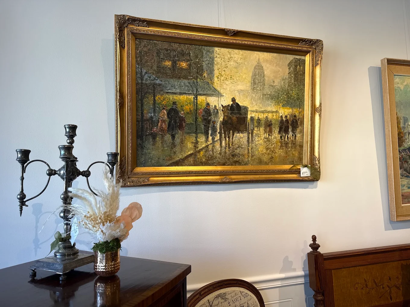Framed street scene painting above an antique console